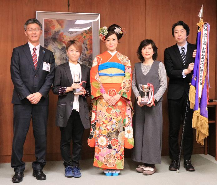 オレンジ系の華やかな中振袖を着たモデルを真ん中に、記念撮影をする種岡さんと櫻井市長ら