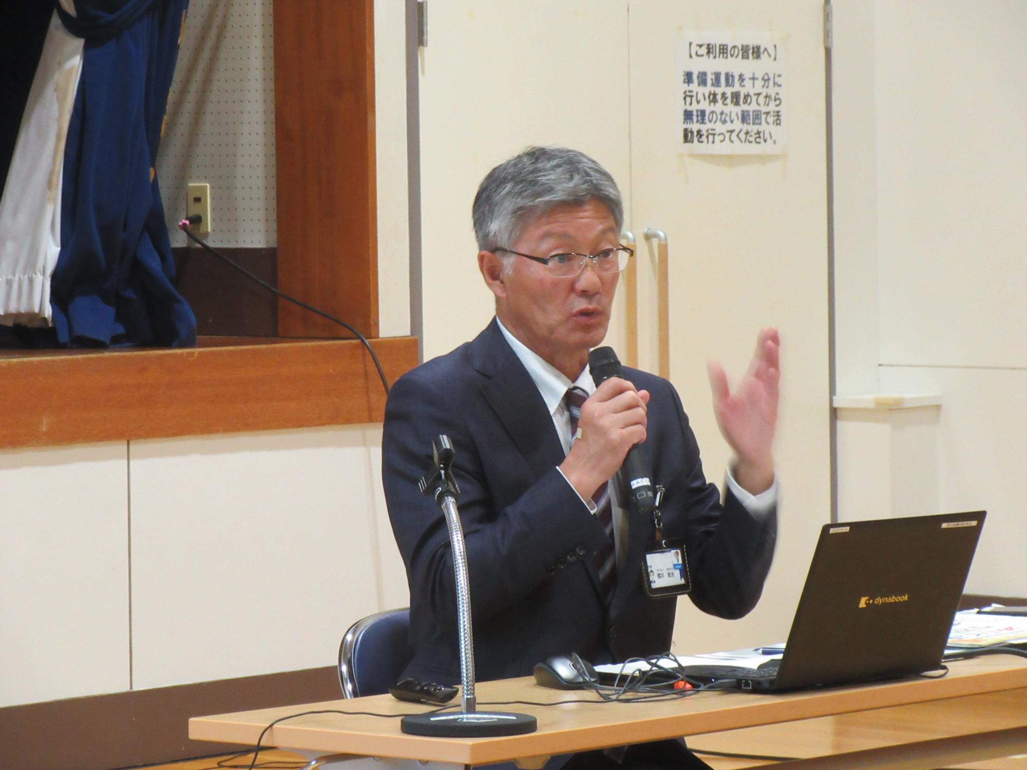 写真：マイクを持ち住民の皆さんと意見交換を行う市長