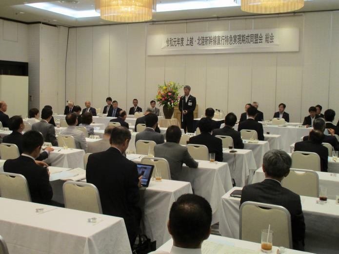 多くの来賓、会員が座っている前であいさつしている市長の写真