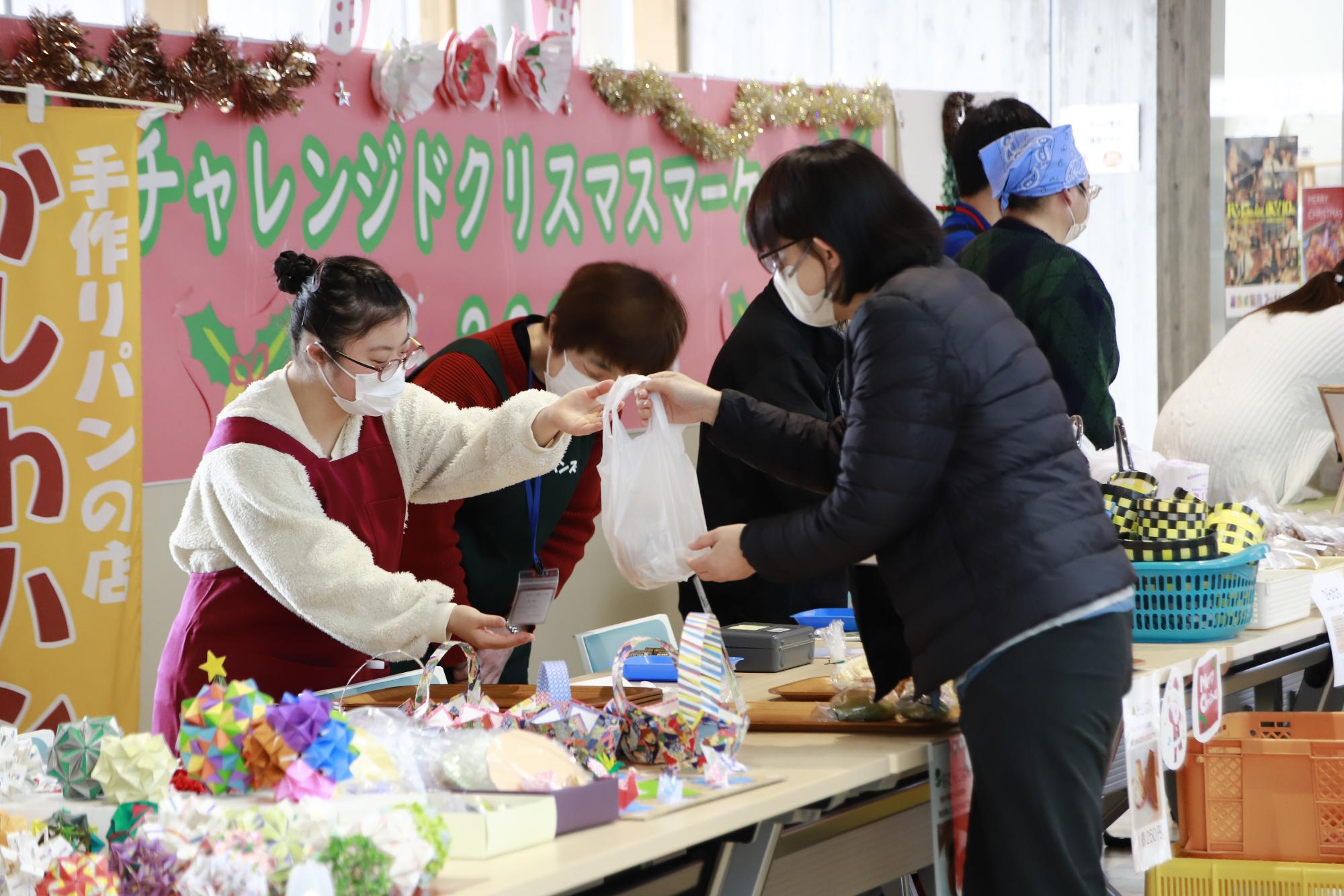 写真：かしわハンズの利用者・スタッフが、袋に詰めたパンをお客さんに手渡しているところです。（12月23日）