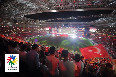 写真：デフリンピック過去大会の開会式の様子。ドーム型の会場に多くの選手・観客が集まっています