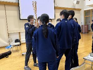 東京2020オリンピック・パラリンピックの聖火ランナートーチを持って生徒に説明する津吉医師