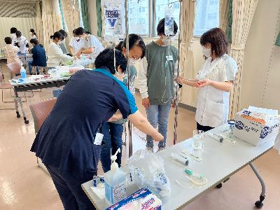 写真：点滴の交換方法を学ぶ参加児童