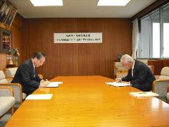 会田柏崎市長と柏崎信用金庫の理事長が向かい合って座り、協定書にサインをしている写真