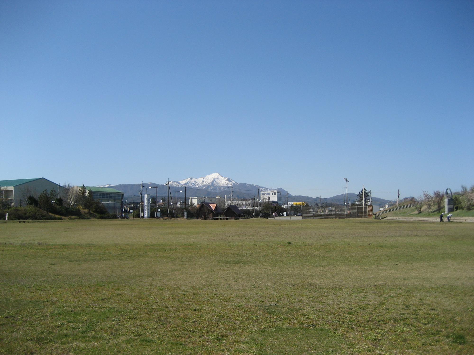 写真：準備運動やストレッチをする芝生広場。米山が遠くに見えます。