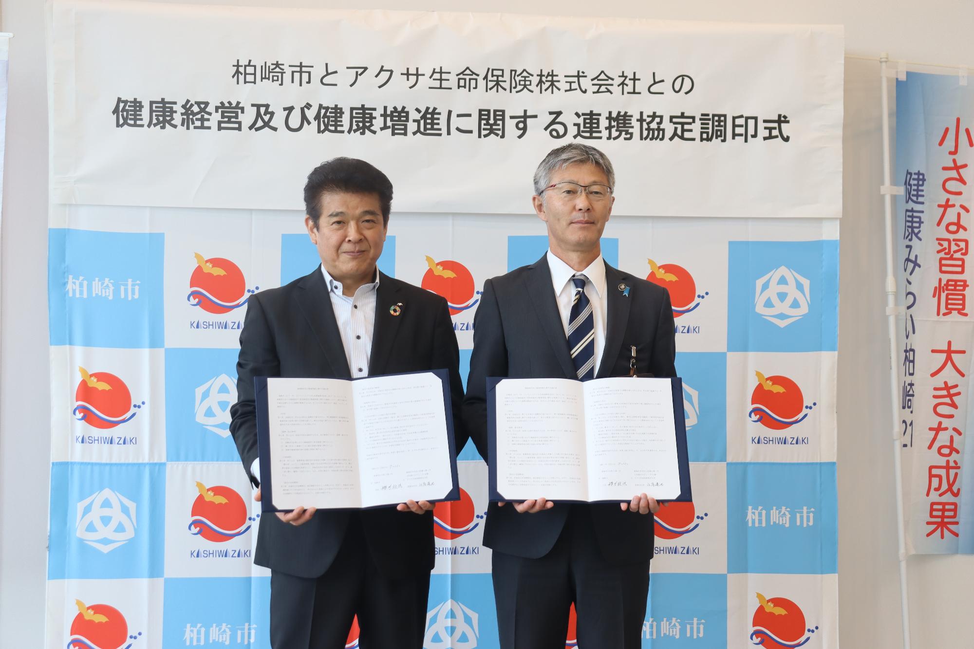 写真：桜井市長とアクサ生命保険株式会社の関係者が並んで、取り交わした協定書を胸の前に掲げています。