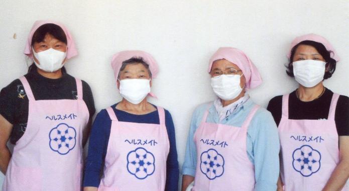 ピンクのエプロンを着た食生活改善推進員が4人ならんでいる写真