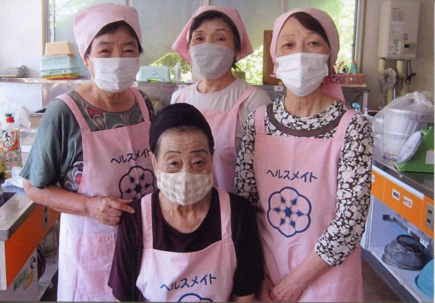 写真：ピンク色エプロンを身に着けた4人の女性