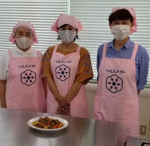 写真：ピンク色のエプロンと三角巾を身に着けた高田地区食生活改善推進員の3人の女性