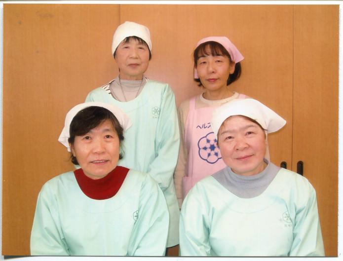 エプロンと三角巾を着用した食生活改善推進委員四人の女性が前方に2名座り後方に2名立っている写真