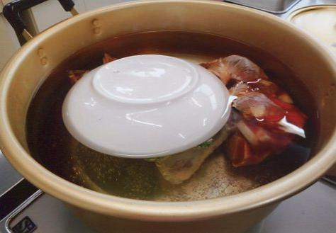 写真：熱湯の中に材料の入ったポリ袋を入れ、落し蓋をしているところ
