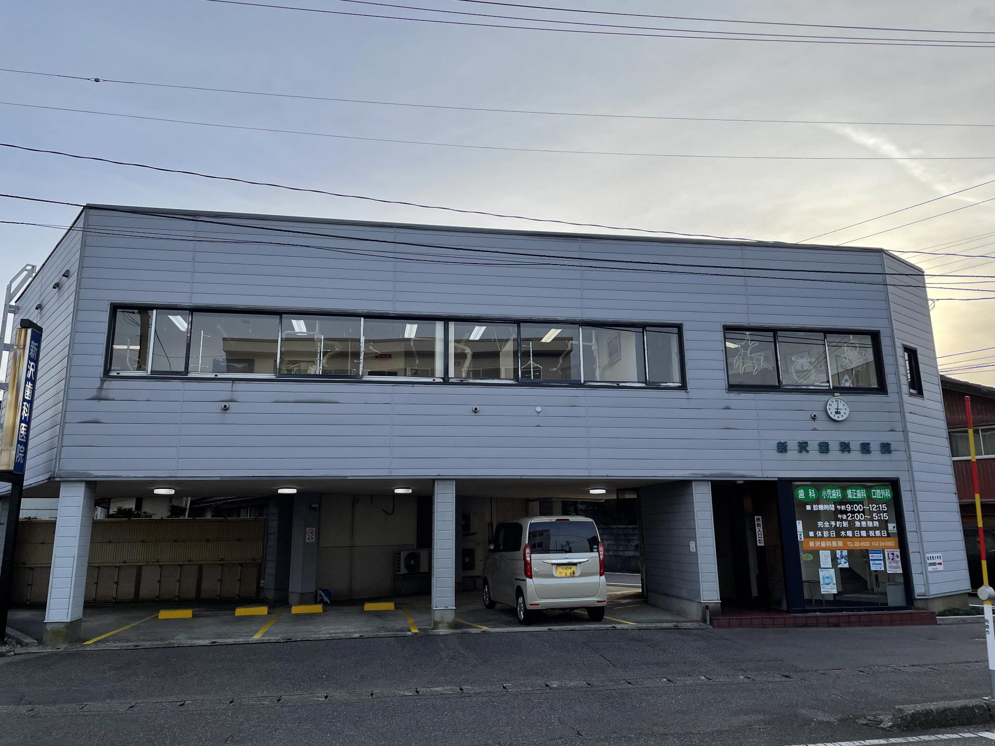 新沢歯科医院の外観写真。医院は2階で、1階は屋根付き駐車場があります。