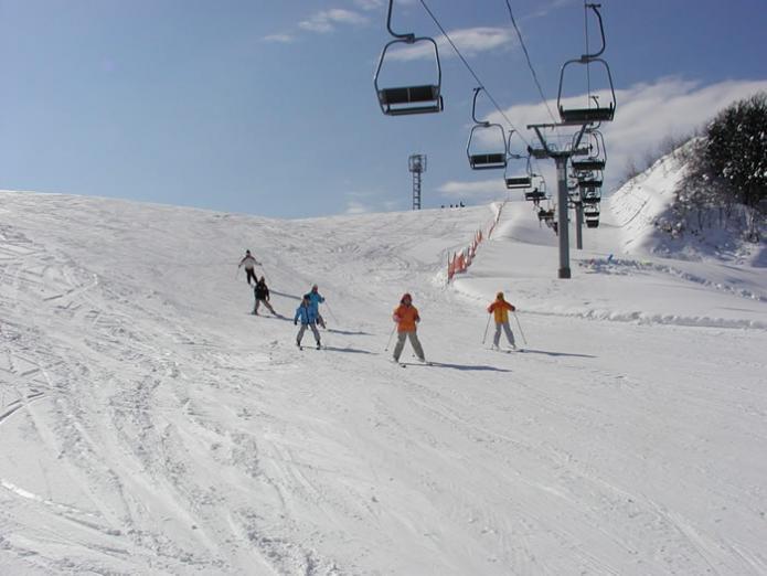 一面の雪景色とリフトと斜面を下っている5人のスキーヤーの写真