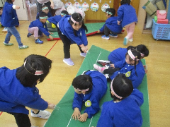 写真：年少児と年中児をマットに乗せて、年長児が引っ張っているところ