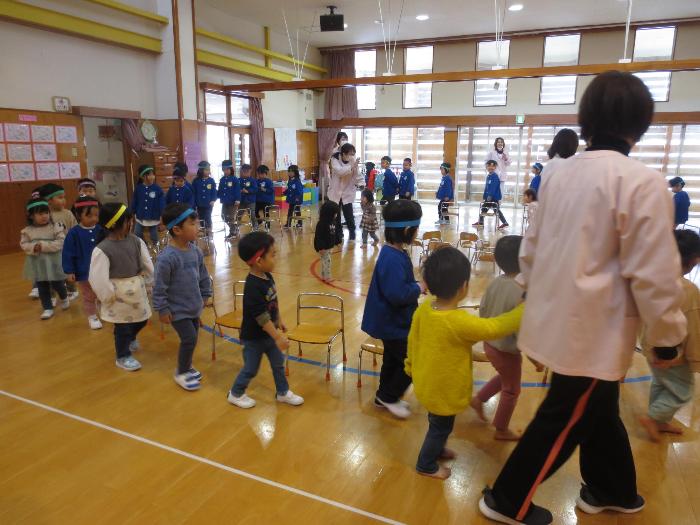 写真：全園児が参加した椅子取りゲーム。遊戯室にたくさんの椅子が並び、その周りを子どもたちが音楽に合わせて回っています