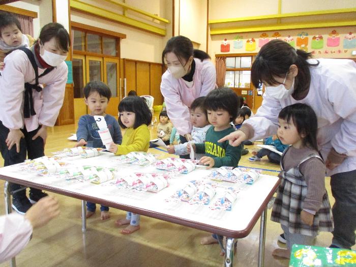 写真：机に並んだお楽しみ行事の景品を選ぶ0・1歳児の子どもたち