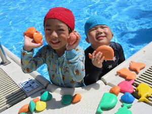 写真：小学校のプールで、4歳児が水中にもぐってで拾った貝のおもちゃをプールサイドに並べています。