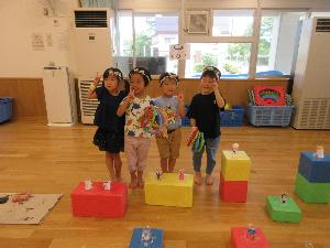 写真：ソフト積み木の上におもちゃを並べた輪投げ屋さん。担当の子どもたちが立って並んでいます。
