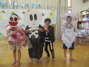 写真：黒いビニール袋や白い布をまとって、手作りのお化けに変身してポーズをとっている5歳児