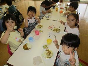 写真：完成したカレーをおいしそうにほおばる4・5歳児4人