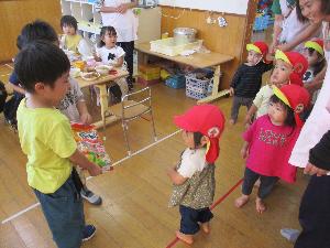 写真：買い物してきたおせんべいを、きりん組3歳児の保育室へ届けた1歳児たち