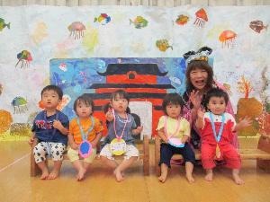 写真：乙姫さまと一緒に竜宮城の前で並んでいる1歳児