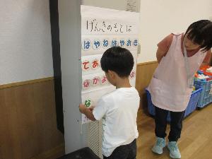 写真：年長児がキーワードカードを壁のポスターに貼り、健康ワードを作っています。