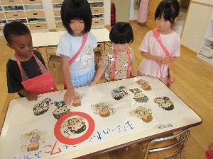 写真：食事マナーの間違い探しゲームをする子どもたち。間違えているイラストを丸で囲っています。