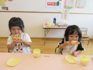 写真：子どもたちが自分たちで具材をのせて作ったピザトーストを食べています。