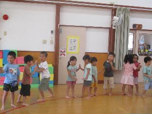 写真：向かい合ったお友達と片手を合わせ、力加減を調整しながら押し合う3歳以上児