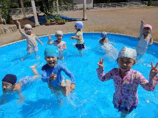 写真：組み立て式の大きなプールで泳いだりポーズをとったりする3歳児