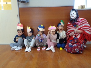 写真：お面をつけた福の神と2歳児5人が並んでいます