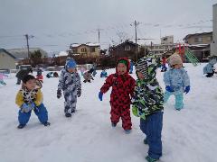 写真：雪の上を笑顔で歩くぱんだ組の子どもたち