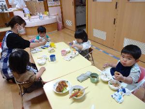 写真：4人の園児が嬉しそうに給食を食べています