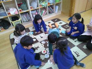 写真：3歳児がかるたをしている写真。一人の男児が札を取りに行っています