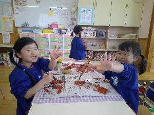 写真：茶色の絵の具がついた手を、カメラに向かって見せる2人の女の子