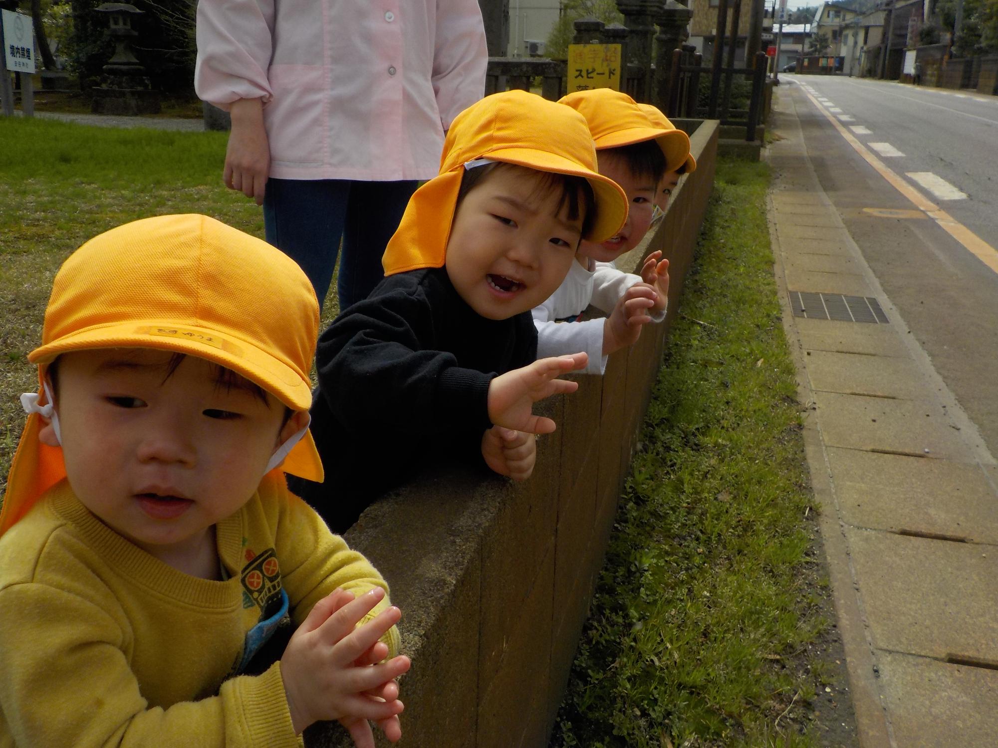 写真：4人の子ども達が通り過ぎる車に手を振っているところ