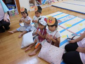 写真：ジュース屋さんでもらったリンゴジュースをおいしそうに飲むうさぎ組の子どもたち。