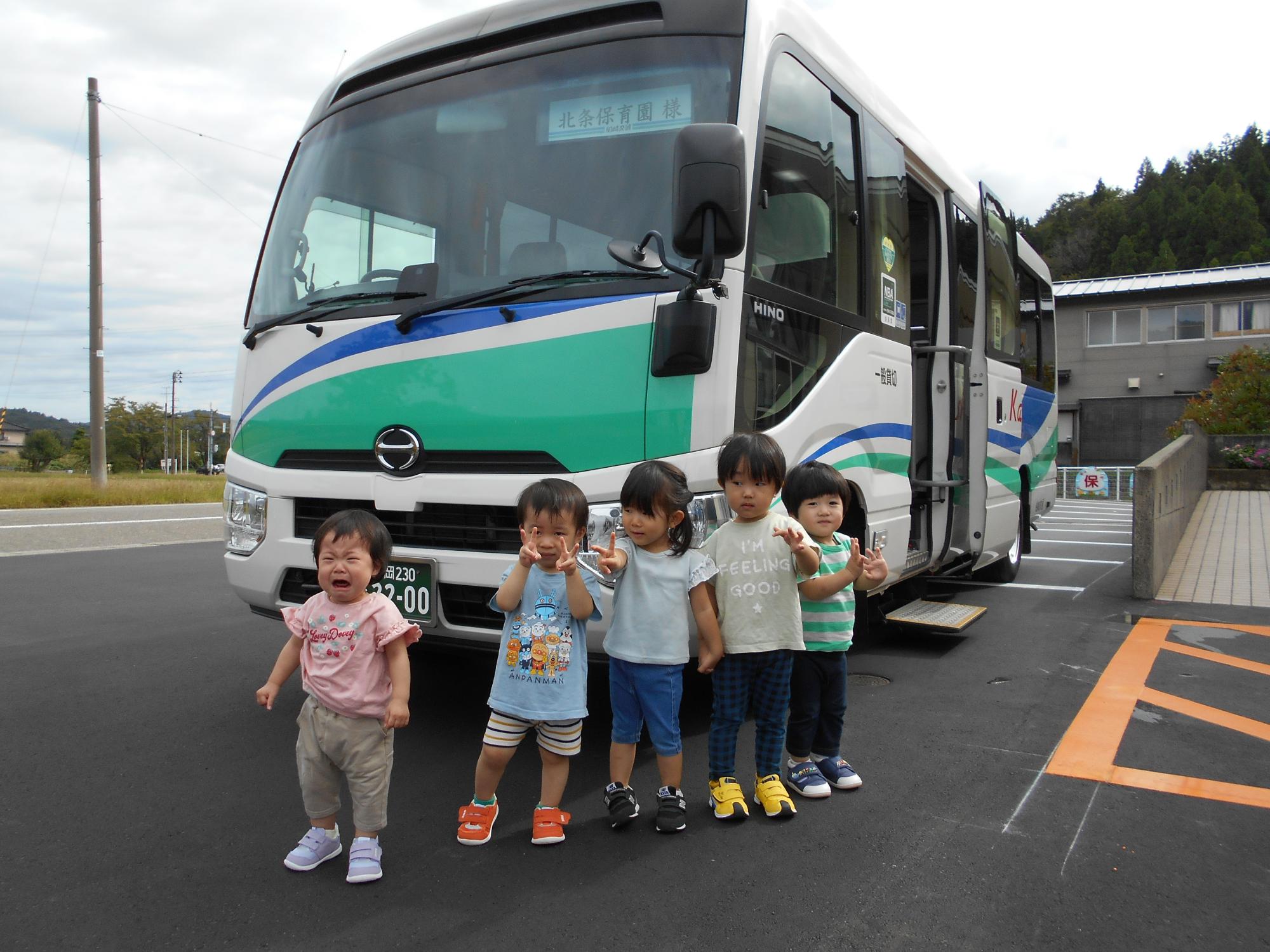 写真：園の駐車場に停車したバスの前に、5人の子どもたちが並んでポーズをとっています
