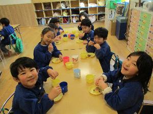 写真：おやつの時間に年中児8名がクッキーを食べています。飛び切りの笑顔を見せてくれました。