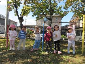 写真：公園の鉄棒にぶら下がって遊んでいる2歳児の様子