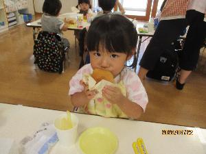 写真：両手でハンバーガーを持ち、おいしそうにほおばる2歳児