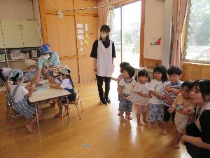 写真：ぞう組がカレーの材料を着る様子を、並んで見学する2歳児