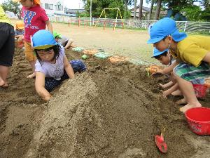 きりん組の男児2名と女児1名が砂場で山を作り、トンネルを作っているところ