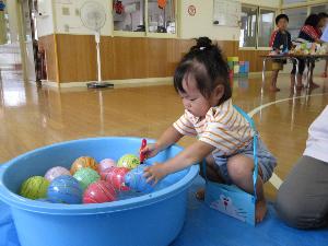 写真：2歳児1人がタライの中の水風船をおたまですくおうとしています。