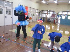 写真：鬼と一緒に豆にみたてたボールを投げる子どもたち