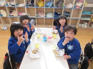 自分たちで作ったクッキーを午後のおやつの時間に食べているぞう組の子どもたち4人の写真