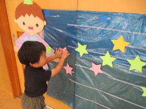 写真：壁に貼られている彦星と天の川に星を貼るぱんだ組の男児