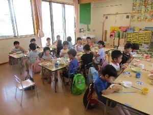 写真：給食の時間に椅子に座りながらカレーを美味しそうに食べているらいおん組