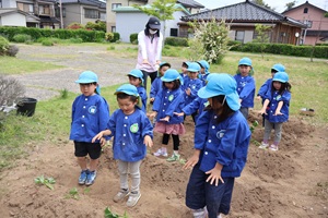 写真：子どもたち、野菜が大きく育つようにと両手の平を畑に向けてでパワーを送っています